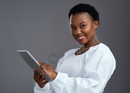 只需单击一下 您就可以让您的梦想成真 一名年轻女子站在灰色背景下使用数字平板电脑背景图片