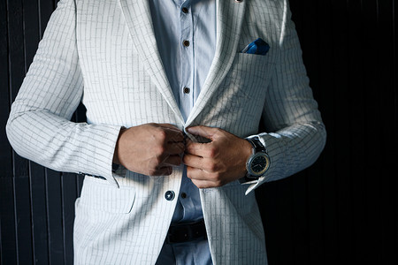 领带扣时尚新郎在夹克上扣纽扣人士男性按钮阴影手指男人服装衣服蓝色领带背景
