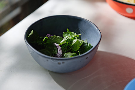 紧贴新鲜采到的basil树叶     白桌底面海军蓝瓷碗中的香食烹饪草药背景图片