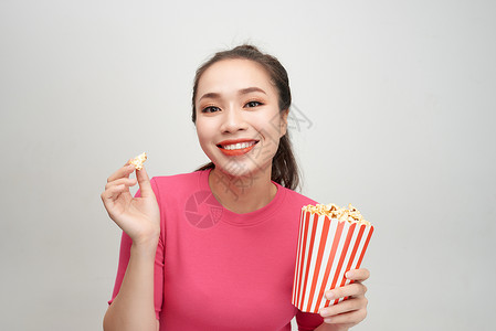 一个快乐的漂亮女孩的肖像 吃爆米花 孤立于白色背景娱乐乐趣女士微笑女性电影电视背景图片