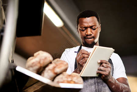 一位男性面包师在面包店工作时做笔记的 我当时正在准备我的订货单背景
