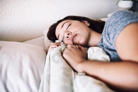 充足的睡眠是一种自我保健的方式 一个迷人的年轻女人早上在家里睡在她的床上背景