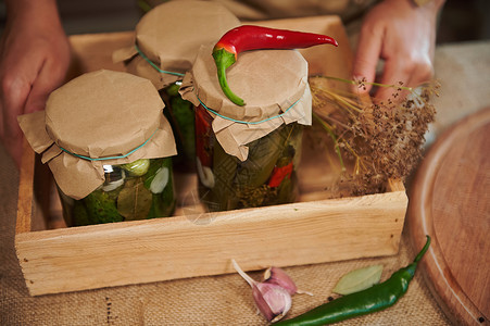 切成一幅木箱的景象 装有罐子和美味自制甜美菜菜瓜黄瓜和红辣椒背景