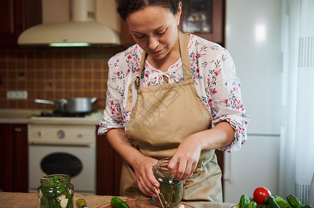 迷人的家庭主妇 漂亮的漂亮女人 在家庭厨房内烹饪咸黄瓜 准备自制的美食背景图片