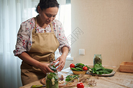 迷人的中年女子在家庭厨房内烹饪黄瓜 准备自制的美食;为她们做饭背景图片