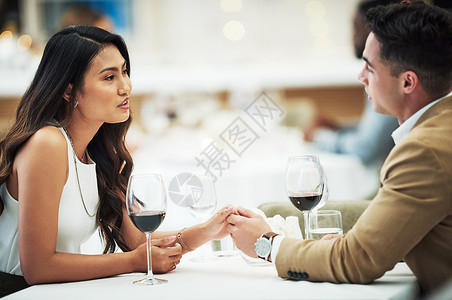 今晚吃鸡浪漫在今晚的桌子上 一个可爱的年轻夫妇手牵手坐在餐厅的餐桌边 (笑声)背景