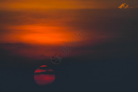 美丽的夕阳 太阳在日落时被云环绕 阳光照耀着振奋人心的橙色红云红太阳橙子红色黄色天空石头乌云地平线风景背景图片