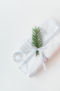 一个用白色牛皮纸密封的自制圣诞果子蛋糕 连同一棵圣诞树的小枝 放在白色背景上 礼品包装背景图片