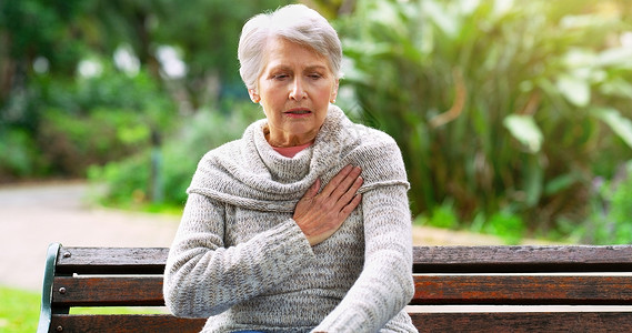 这不是一个好兆头 在公园外 一位压力山大的老妇人坐在长椅上 手捂着胸口感到不适背景