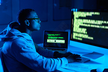 电脑黑客素材一位年轻的男性黑客在黑暗中破解了电脑密码 他把电脑密码弄得一团糟代码信息技术男人笔记本刑事成人成年人数据互联网安全背景