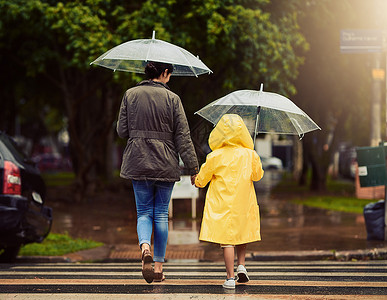 我们一直在路上在路上 我们冒雨前行 后视镜头 一个面目全非的小男孩和他的母亲手牵着手在外面的雨中行走背景