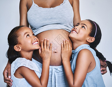 一个幸福的家庭 白天 两个快乐的小女孩站在家里怀孕的母亲旁边背景图片