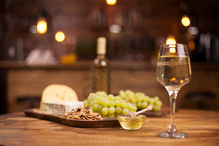 一杯白酒旁边一碗美味的金蜂蜜美食桌子玻璃盘子乡村食物照片水果坚果生活背景图片