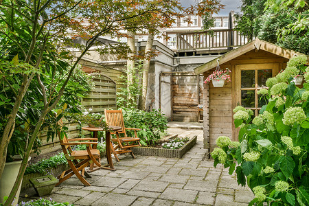 花园桌子带有坐地的Neat天台花园后院家具石头桌子植物院子庭院铺路扶手椅背景