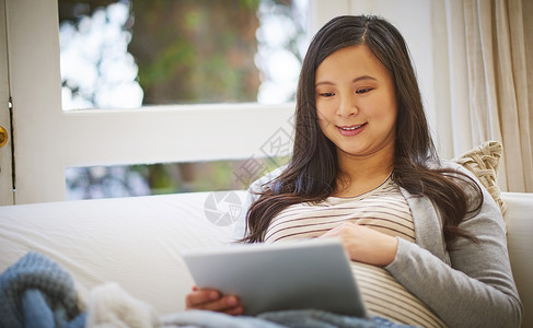 怀孕妇女在家里使用数码平板电脑 在网上发现的东西总是有新奇之处背景图片