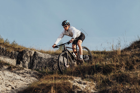 专业赛车手在他山上骑着一辆自行车 从山下下奔下山去的运动员活力运输太阳镜娱乐冒险男人速度闲暇山地运动年轻的高清图片素材