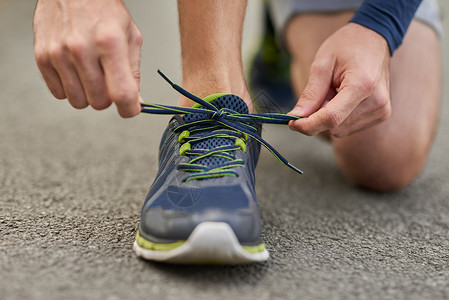 确保你的鞋带系好 一位面目全非的男跑步者在户外锻炼时系鞋带的高角度拍摄背景图片