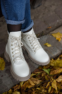 女款潮鞋穿牛仔裤的女腿和带鞋带的白色时装靴季节达人工作室靴子衣服潮人石头公园购物女性背景