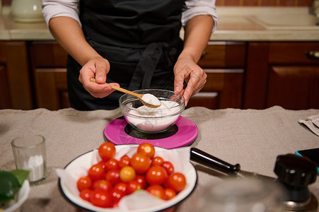 围裙详情详情 家庭主妇的手握着木茶匙 在煮番茄和罐头时称厨房糖量重背景