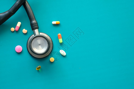 绿色背景的彩色药丸和听诊器背景图片