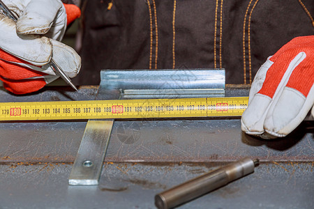 钻孔时在金属表面的标记 工人使用一种工具测量和标记铁表面 以作标记背景图片