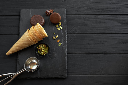 creamCookies N' Cream 冰淇淋的配料 包括巧克力和饼干 坚果 甜筒 桶和散落在石板上的金属勺 俯视图背景