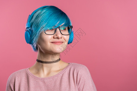 漂亮的年轻女孩 有着绿松石色的头发 在彩色背景下的工作室里玩得很开心 微笑着 戴着蓝色耳机跳舞 音乐 舞蹈 广播概念成人收音机情背景图片