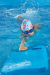 小女孩学会游泳 在室内游泳池与游泳池板女孩游泳者游泳板学校婴儿木板练习学习教学班级背景图片