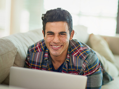 您应该亲自尝试一下写博客 一个英俊的年轻人在家里的沙发上放松时使用他的笔记本电脑的画像背景图片