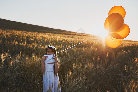 一个可爱的小女孩 站在玉米田里的时候 给一堆气球写了一封信 - 是的 长官背景图片