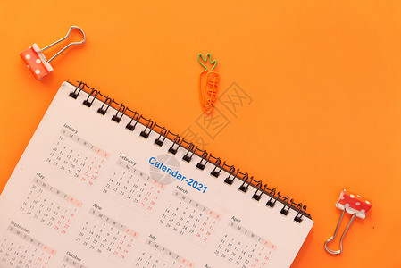 新的年目标概念 与2021年关于颜色背景的日历蓝色橙子眼镜新年紧迫感铅笔背景图片