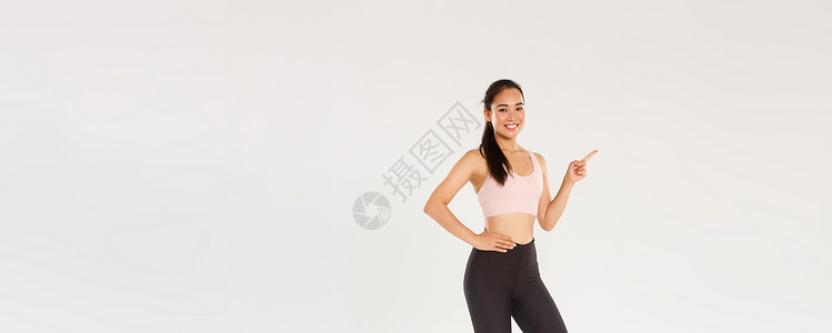 会员专属福利运动 健身房和健康的身体概念 穿着运动服的全长微笑美丽的亚洲女运动员 向左指指点点 展示广告 健身房会员资格或运动器材训练女性成背景