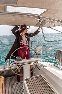 极富魅力的中年女子在夏日主持游艇 豪华夏季冒险 户外活动双体海滩方向盘车轮假期运输船长女士晴天海洋背景图片