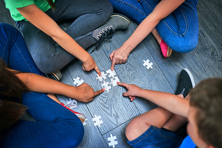 拼图中小朋友帮助学习过程的完美游戏 一群孩子在地板上一起玩拼图的高角度拍摄背景