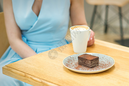 坐在咖啡厅桌边的年轻女子紧缩餐厅桌子美食面包烹饪巧克力食物咖啡杯子图片