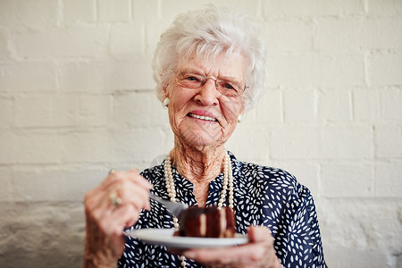 退休从没尝过这么甜美的味道 一个年长的女人在里面吃一块蛋糕背景图片