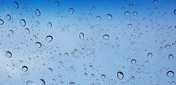 通过窗玻璃表面对蓝色天空的窗口玻璃透视水滴子视角 用于多媒体内容反射环境气泡雨滴飞沫背景天气窗户水滴宏观背景图片