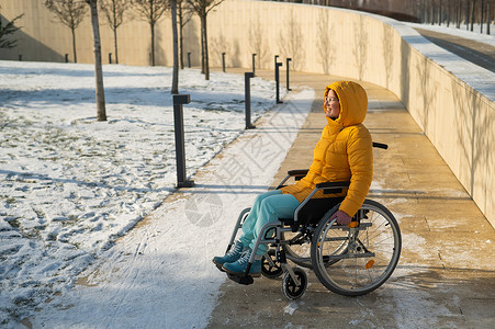 女人在冬季公园坐轮椅放松闲暇事故外套车轮药品卫生女孩机动性快乐保健背景图片