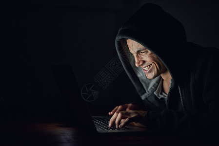 一个蒙面的电脑黑客 在黑暗中用笔记本电脑做暗事高清图片