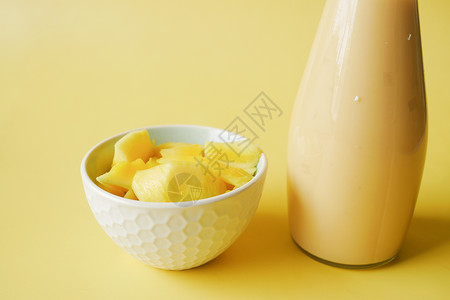 黄底的芒果和新鲜芒果瓶子排毒玻璃橙子奶昔热带果汁牛奶背景图片