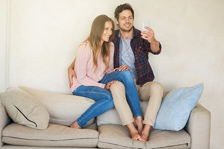 终于白首他终于得到信号了 一个快乐的年轻夫妇 在家里坐在沙发上时一起用智能手机玩耍背景