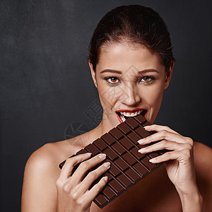 我不能对巧克力说不 演播室拍到一个迷人的年轻女人咬着一块巧克力板背景图片