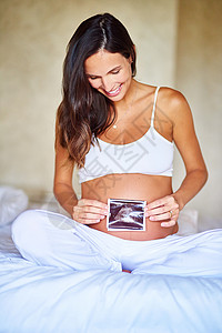 婴儿第一张照片 一个孕妇在肚子前 拿着声波图照片的怀孕妇女背景图片