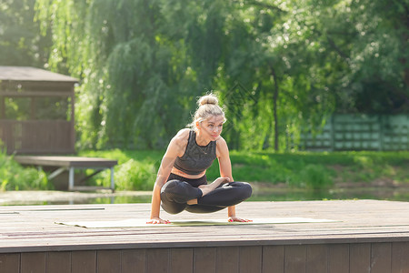 夏天 一位美女坐在垫子上池塘边的木制平台上 做瑜伽沉思冥想金发女郎卫生公园女性平衡体操运动快乐背景图片