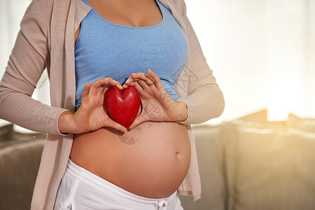 爱从出生前就开始了 一个孕妇在肚子前拿着红心的怀孕女人背景图片