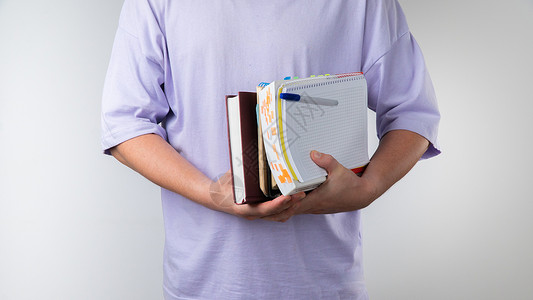 博览群书一个手拿着教科书和笔记本的学生 以白人背景参加班级特写课目背景