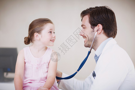 一位男医生用听诊器检查一个小女孩的病情 你的身体状况很完美背景图片