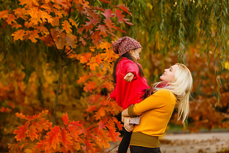 秋天你好毛笔字你好 秋天在城市公园的帽子室外 笑着微笑的年轻母亲和女儿 在秋天玩得开心背景