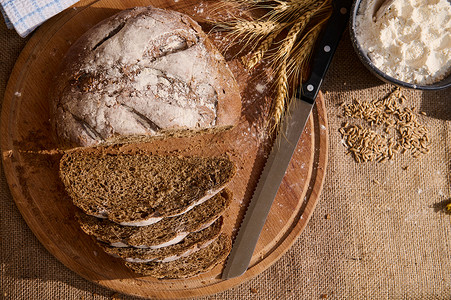 馒头片顶端的新鲜面包 木板上有碎屑 小麦小粉片和薄布桌布上零散的谷物背景