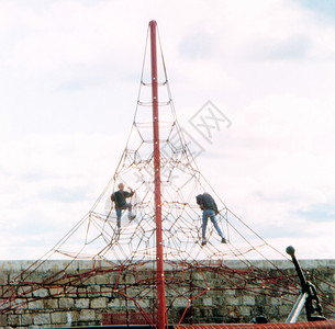 两个年轻人爬上一个高大的游戏架子背景图片